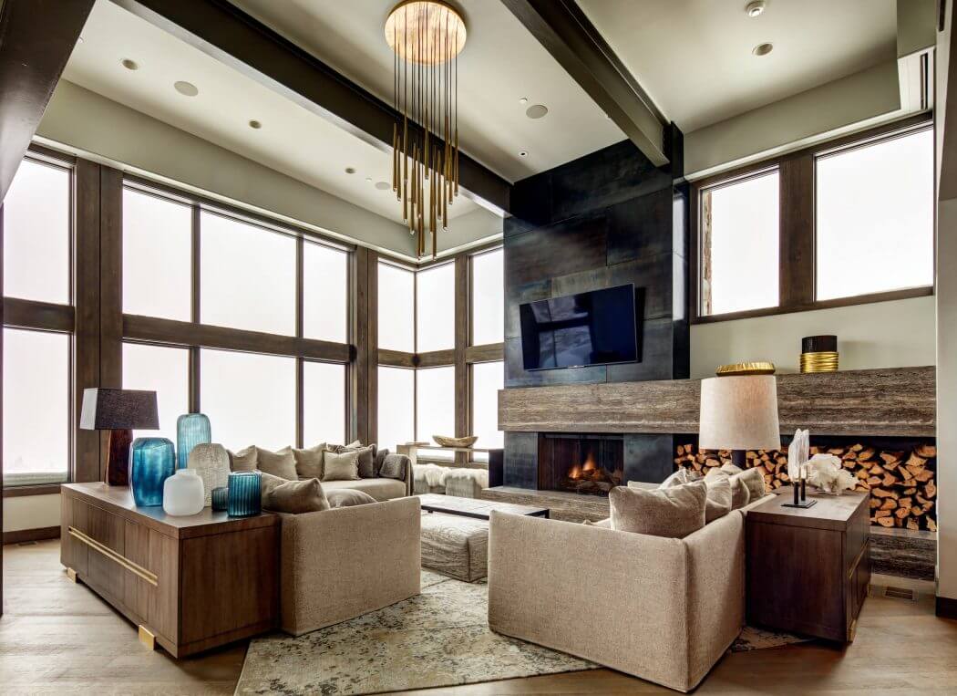 Lavish contemporary living room with towering window wall, sleek fireplace, and striking chandelier.