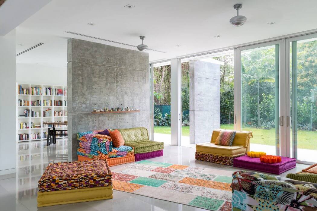Vibrant, eclectic living room with concrete wall, floor-to-ceiling windows, and custom seating.