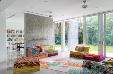 Vibrant, eclectic living room with concrete wall, floor-to-ceiling windows, and custom seating.