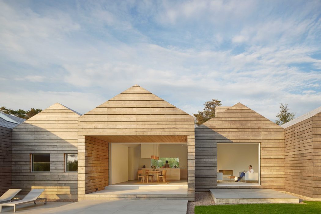 A contemporary wooden residential structure with pyramidal roofs and large windows.