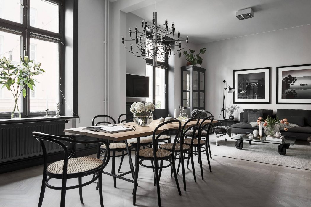 Elegant monochrome dining room with industrial-style chandelier and framed artwork.