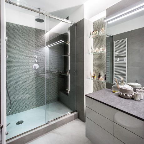 Sleek, modern bathroom with glass-enclosed shower, floating vanity, and tiled walls.