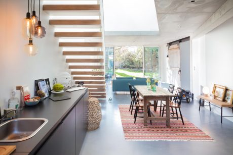 Bright, open-concept kitchen-dining space with wooden beams, glass doors, and eclectic decor.