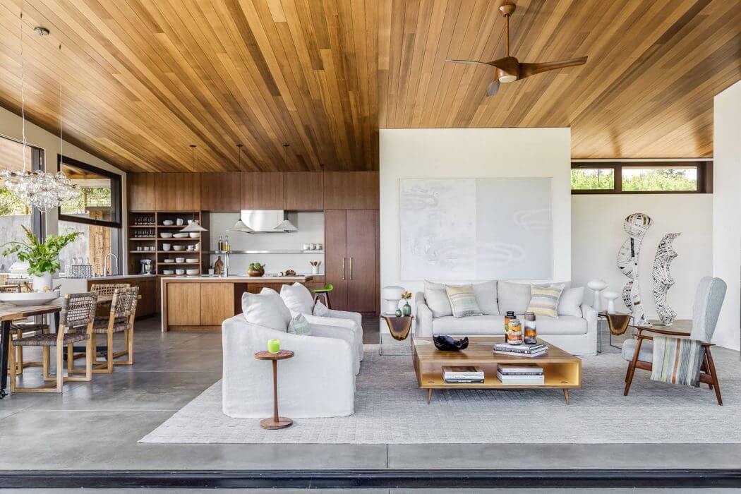 Spacious open-concept living area with wood-paneled ceiling, modern furnishings, and large windows.