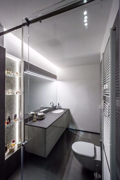 Minimalist bathroom design with black vanity, recessed lighting, and glass partition.