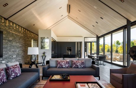 Spacious modern living room with stone accent wall, high ceilings, and large windows.