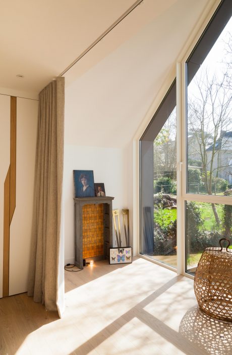 Warm, earthy interior with large windows overlooking lush greenery and artistic decor.