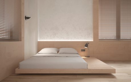 Minimalist bedroom design with wooden platform bed, wall-mounted lighting, and slatted blinds.
