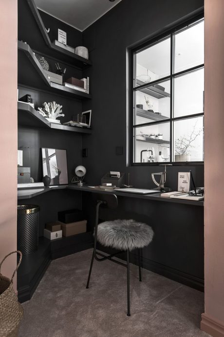 A cozy, monochromatic home office with sleek shelving, large windows, and a plush chair.
