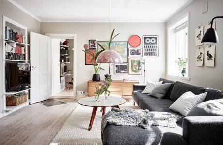 A cozy living room with geometric artwork, wooden furniture, and a plush gray sofa.