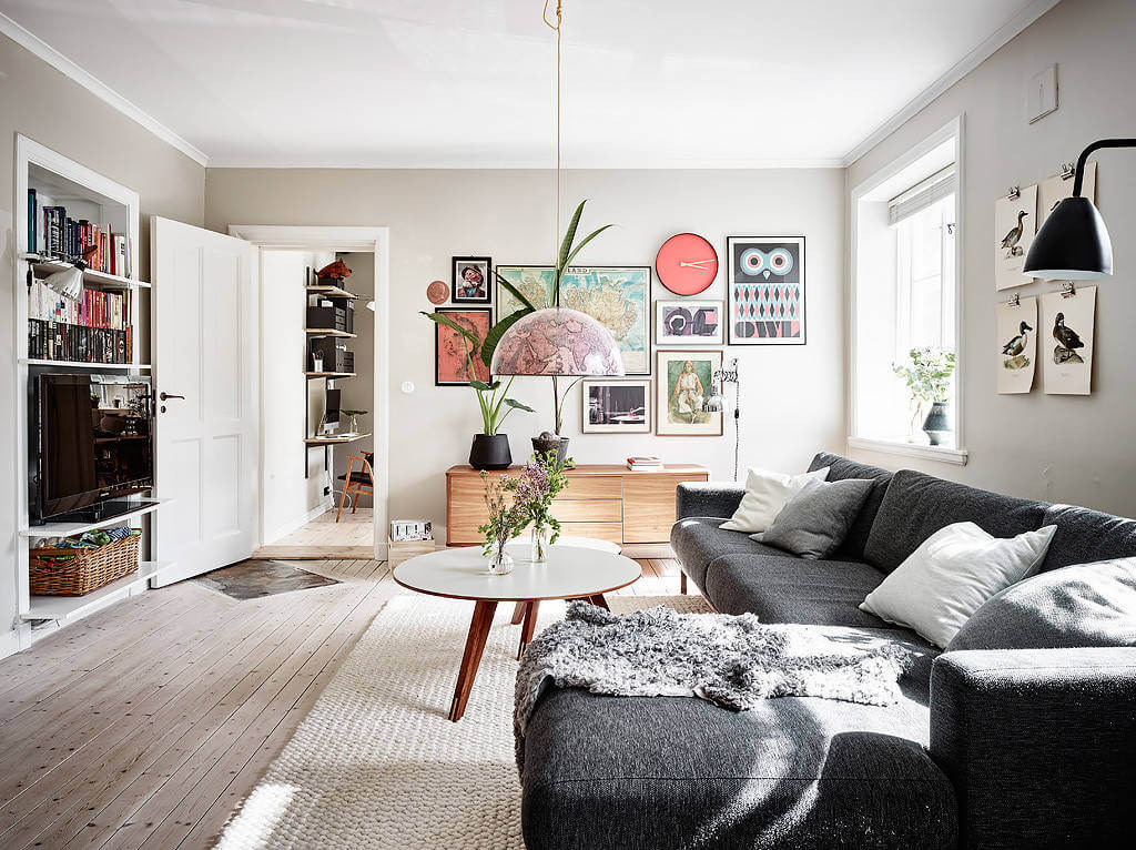 A cozy living room with geometric artwork, wooden furniture, and a plush gray sofa.