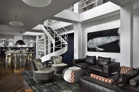 Sleek, modern interior with spiral staircase, black leather furniture, and large artwork.