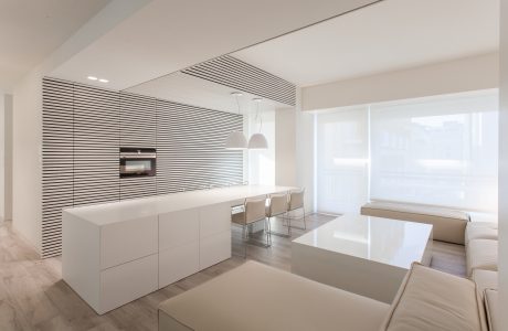 Minimalist kitchen with striped backsplash, built-in appliances, and sleek dining area.