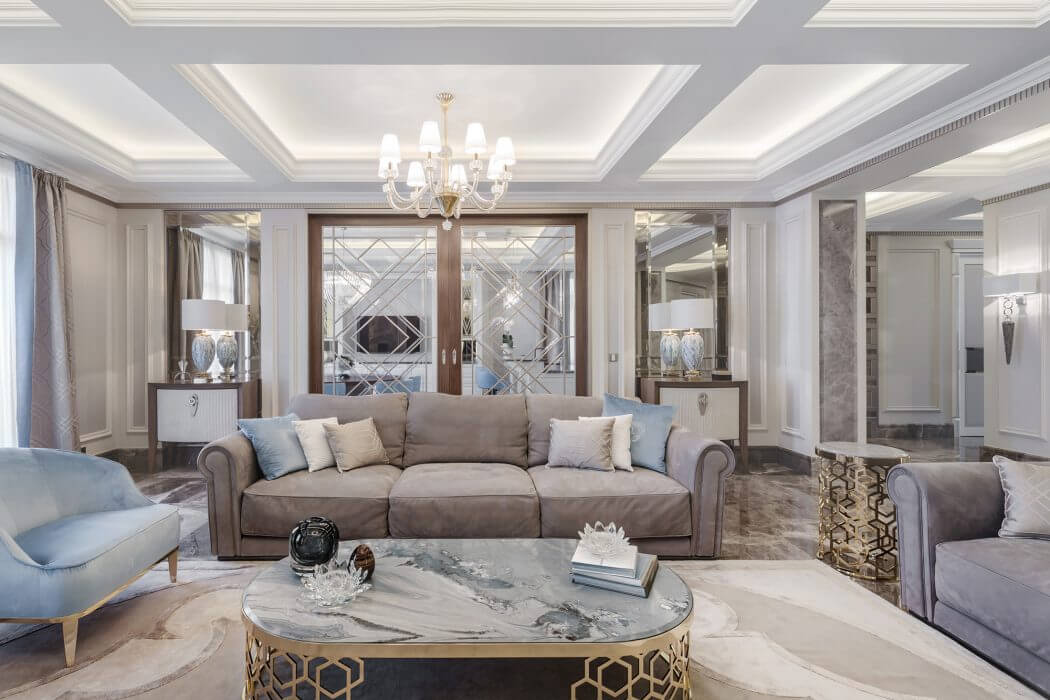 Luxurious living room with elaborate architectural details, ornate chandelier, and stylish furniture.