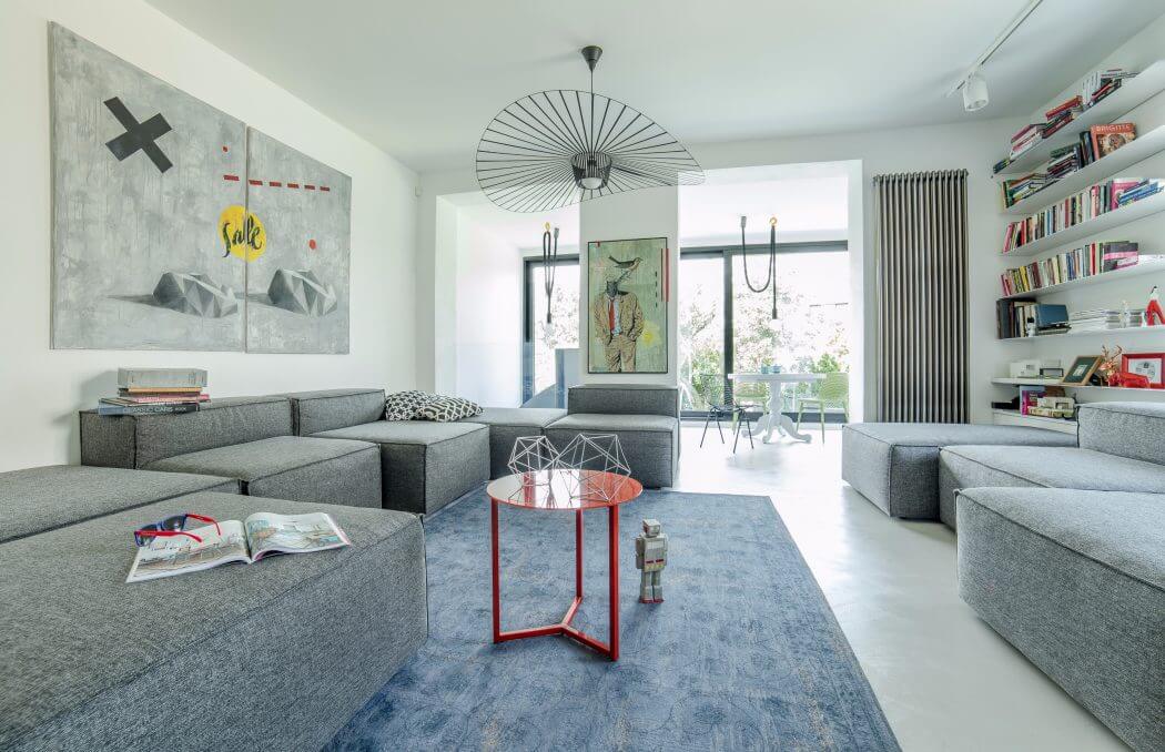 Stylish modern living room with sleek gray sofas, abstract artworks, and minimalist decor.