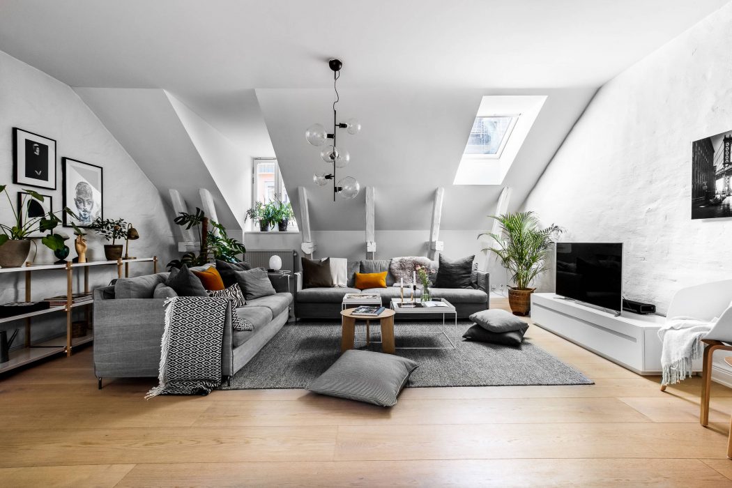A cozy, monochromatic living space with plush seating, eclectic decor, and skylights.