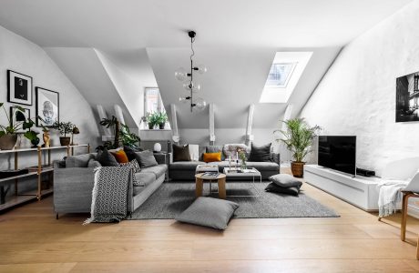 A cozy, monochromatic living space with plush seating, eclectic decor, and skylights.