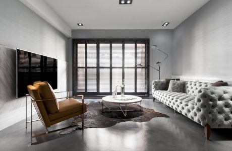 Minimalist living room with tufted sofa, armchair, and coffee table on animal hide rug.