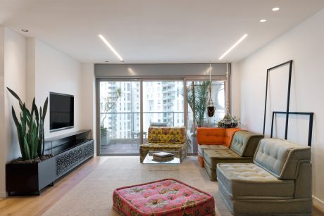 Spacious living room with modern furniture, colorful accents, and floor-to-ceiling windows.