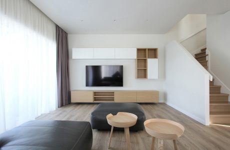 Modern, minimalist living room with floating TV cabinet, wood accents, and cozy seating area.