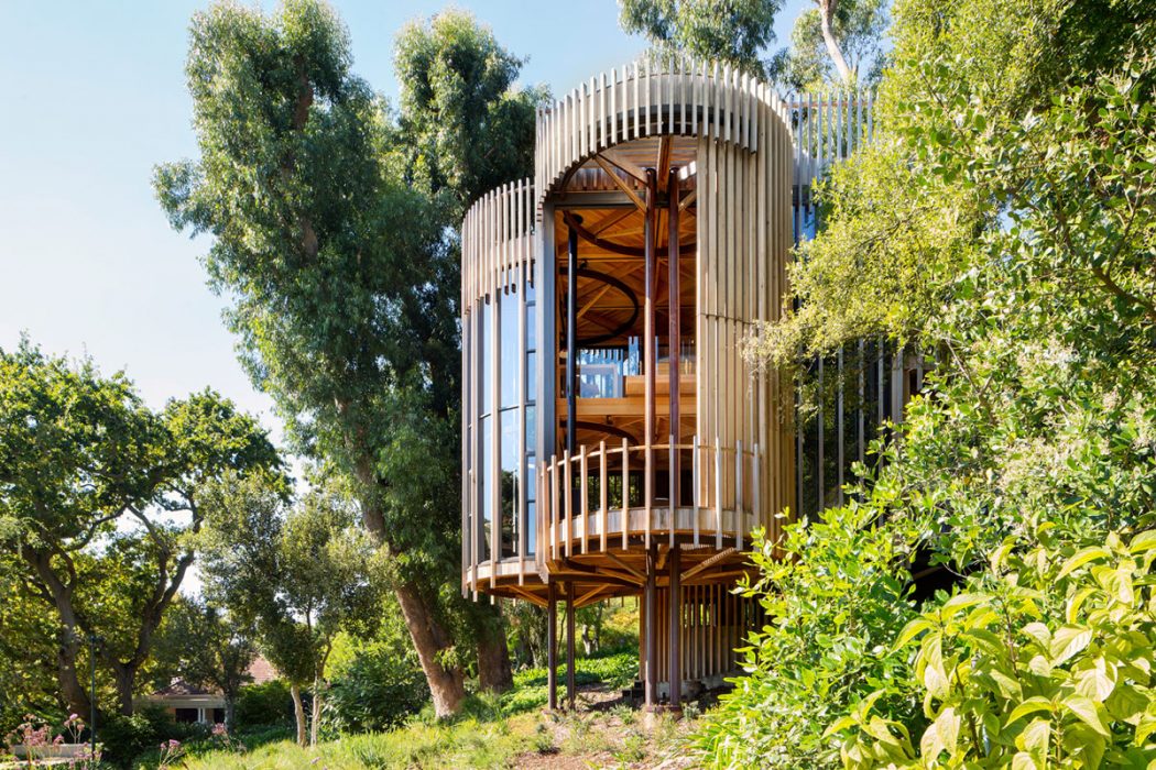 A wooden and metal treehouse-like structure nestled among lush greenery.