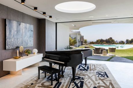 Luxurious living room with grand piano, modern artwork, and expansive outdoor view.