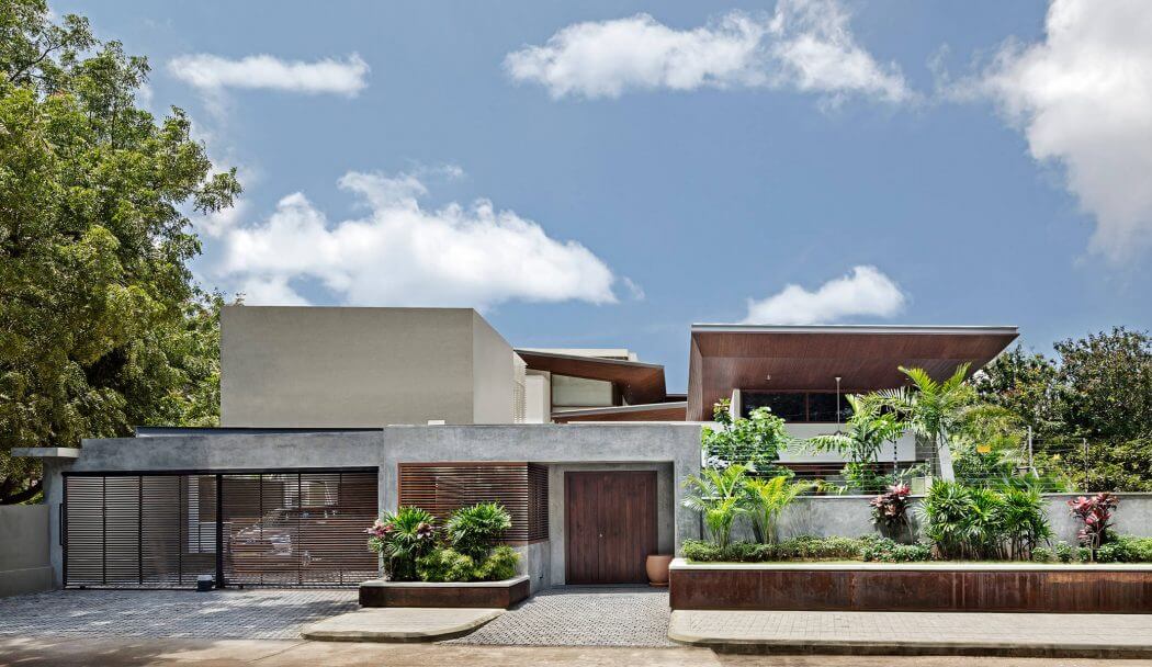 Modern tropical residence with concrete, wood, and lush vegetation design.