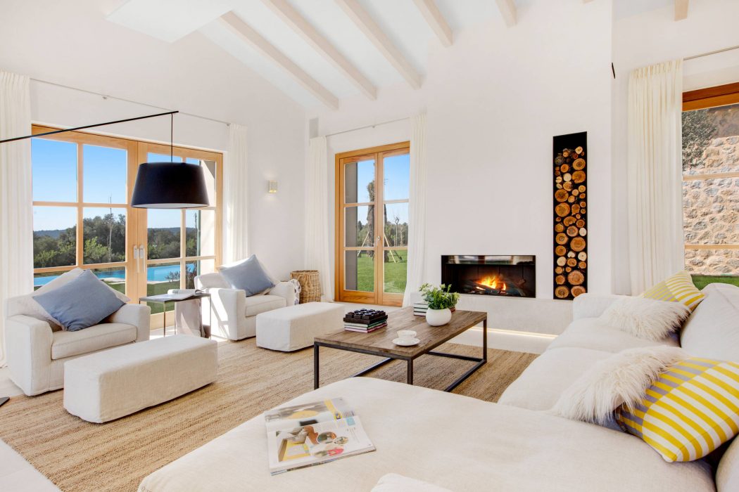 A spacious, well-lit living room with a cozy fireplace, large windows, and modern furniture.