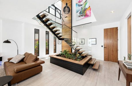 Spacious open-concept room with modern staircase, wooden accents, and indoor planter feature.