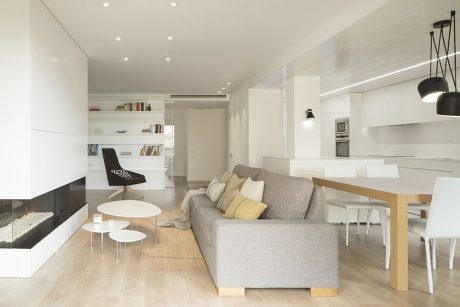 Modern open-concept living space with white walls, wooden floors, and minimalist furniture.