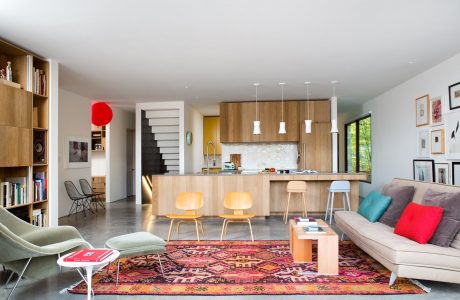 Bright, modern open-concept living space with wooden cabinets, cozy seating, and vibrant accents.