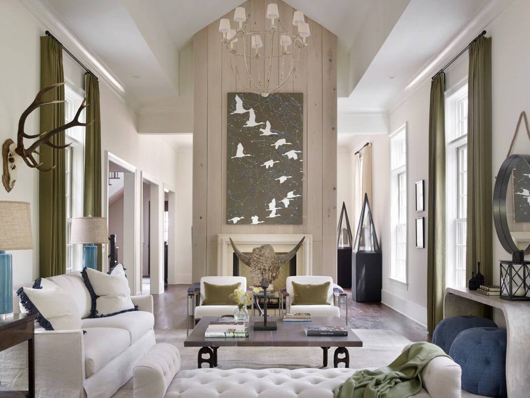 A spacious living room with a high-ceilinged entryway, ornate chandelier, and artistic wall decor.