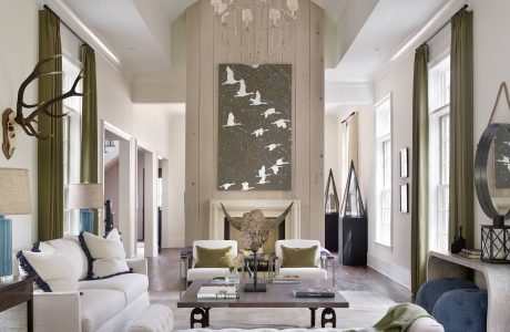 A spacious living room with a high-ceilinged entryway, ornate chandelier, and artistic wall decor.