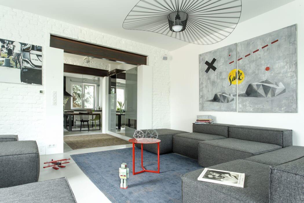 Spacious, minimalist living room with abstract art, geometric furnishings, and modern lighting.