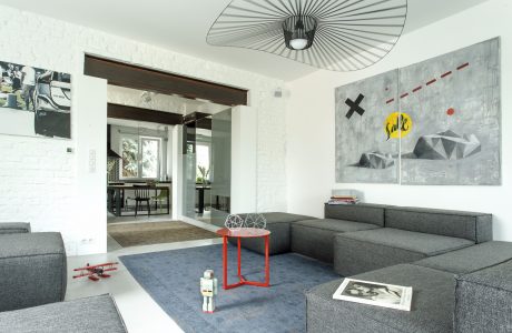 Spacious, minimalist living room with abstract art, geometric furnishings, and modern lighting.