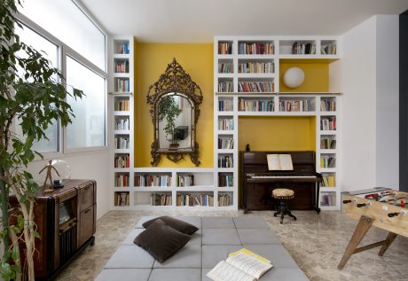 A cozy living room with built-in bookshelves, a grand mirror, and a grand piano, creating a harmonious space.