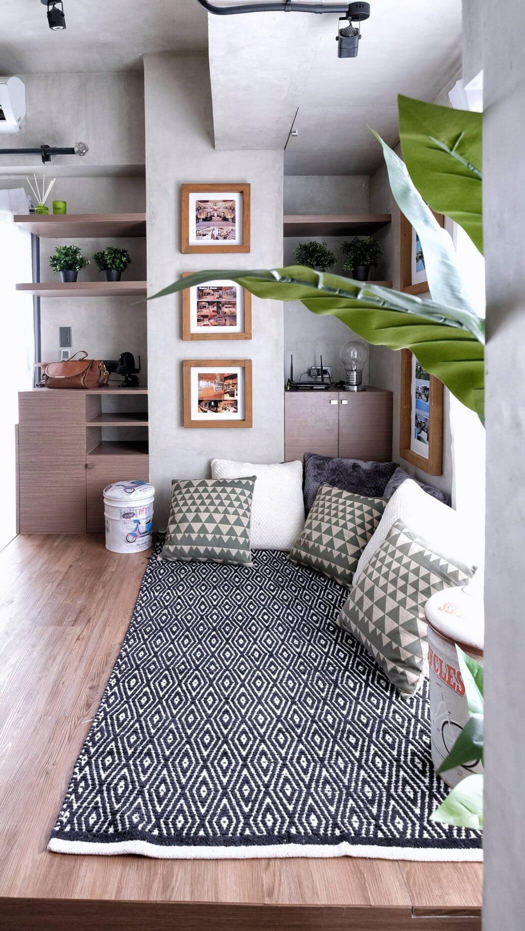A cozy and modern living space with geometric patterned rug, wooden shelves, and lush greenery.