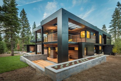 Modern two-story house with wood and steel exterior, large windows, and landscaped yard.