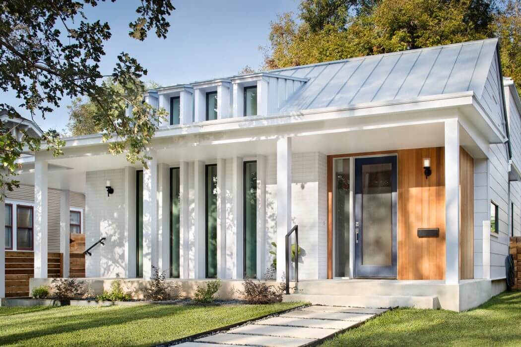 A modern, energy-efficient home with a sleek metal roof, large windows, and an inviting entrance.