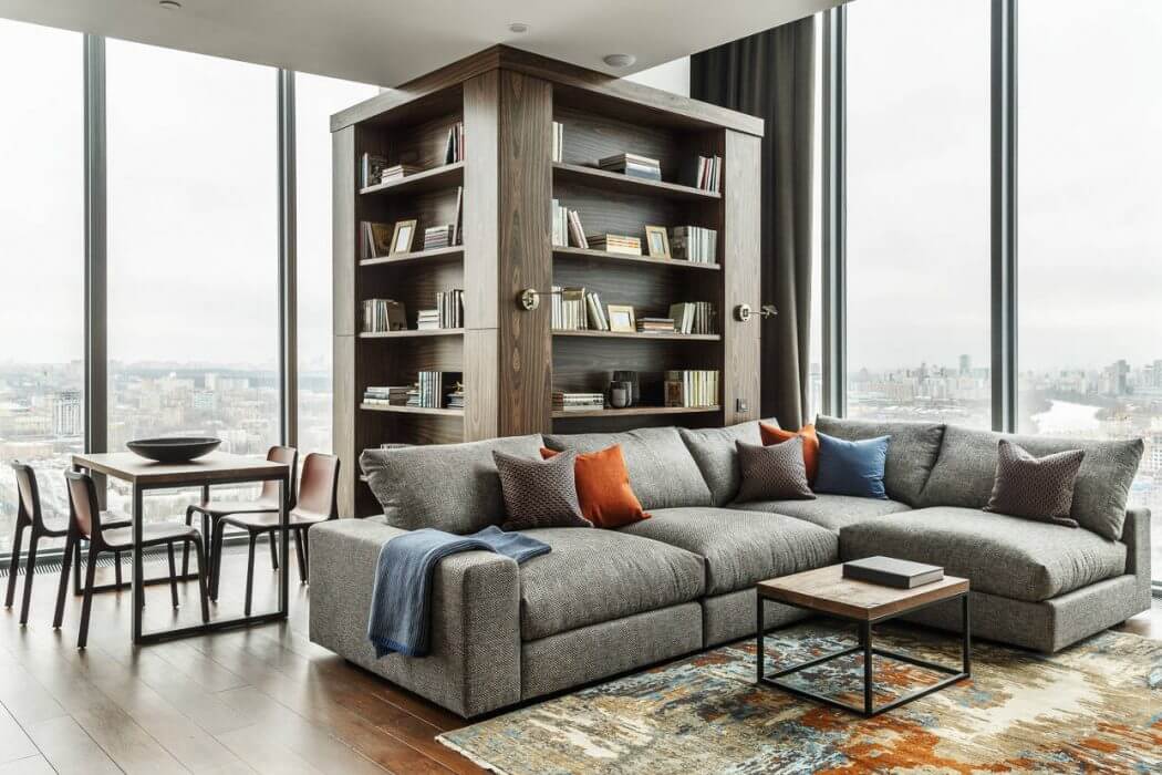 Expansive corner unit with built-in wood shelving, large sectional sofa, and city views.