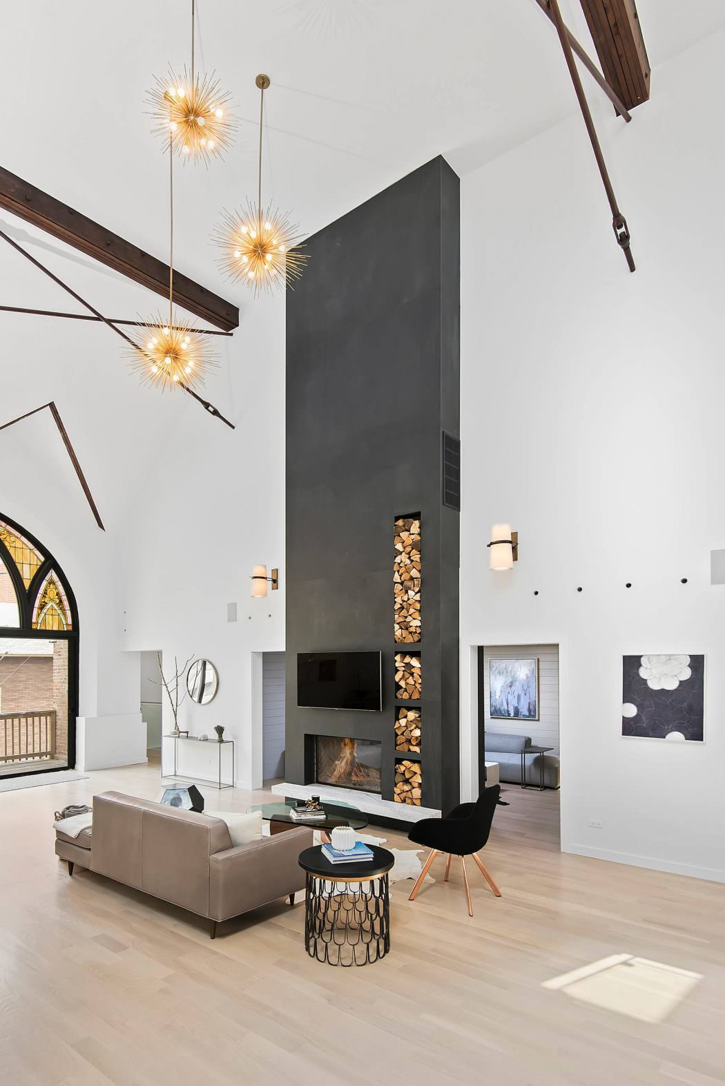 Striking modern living room with sleek fireplace, wood storage, and starburst light fixtures.