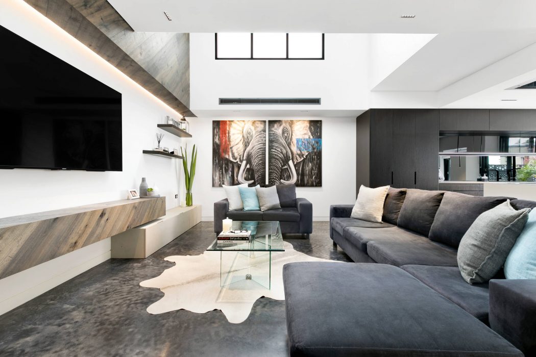Modern open-concept living room with sleek monochromatic palette, large elephant artwork, and glass coffee table.