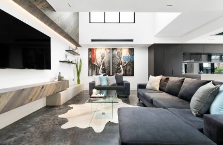 Modern open-concept living room with sleek monochromatic palette, large elephant artwork, and glass coffee table.