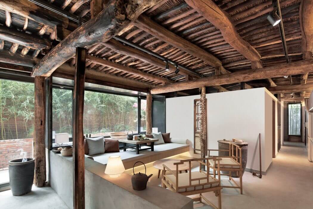A rustic, open-plan space with wooden beams, bamboo accents, and minimalist furnishings.