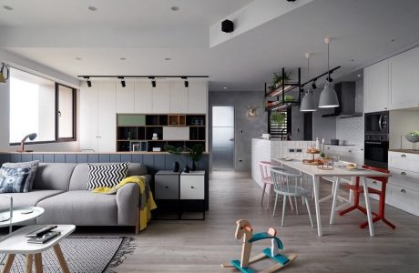 Spacious open-plan living area with modern kitchen, gray and white decor, and stylish lighting.