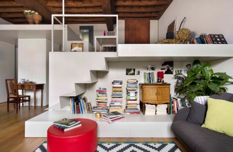 This cozy interior features a warm, rustic-style ceiling, with modern white shelving and an eclectic mix of furnishings.