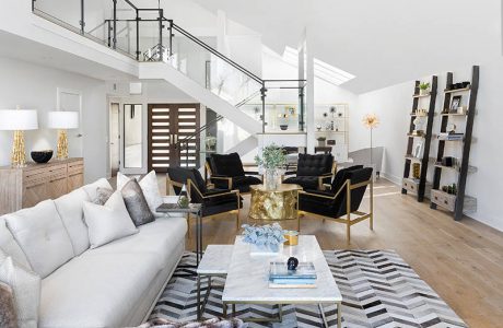 Elegant living space with modern furniture, sleek stairs, and chevron-patterned floor tiles.