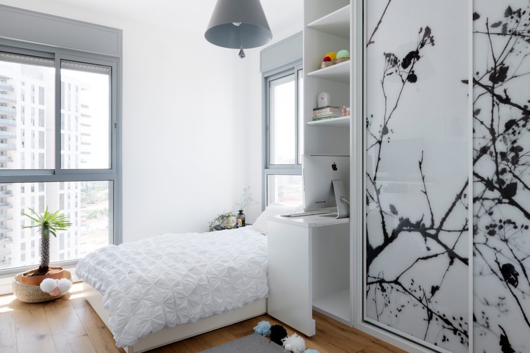 Minimalist bedroom with large window, built-in shelving, and monochrome floral artwork.