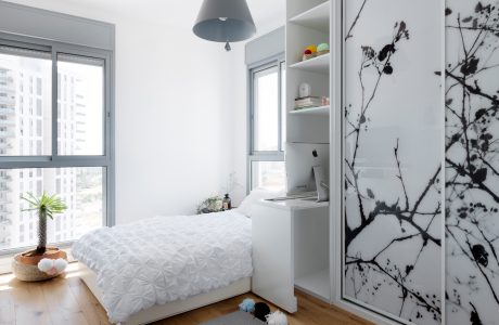 Minimalist bedroom with large window, built-in shelving, and monochrome floral artwork.