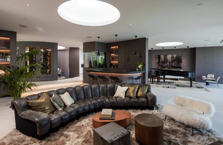 Lavish open-concept living space with modern furnishings, lighting, and bar area.